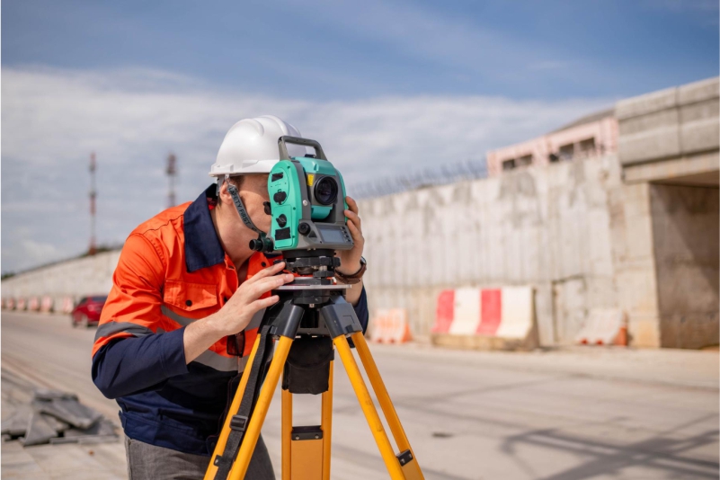 Profissional de agrimensura em campo utilizando estação total